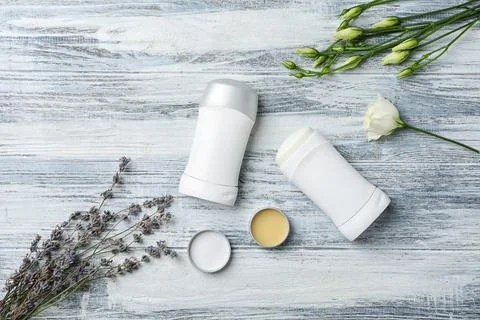 Flat lay composition with different deodorants and flowers on wooden backgrou Foto stock