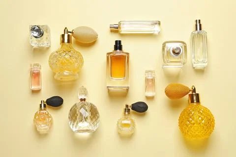 Flat lay composition with different perfume bottles on light yellow backgroun Photos