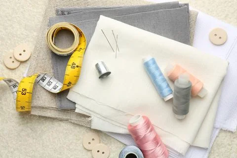 Flat lay composition with different sewing supplies on light textured table Stock Photos