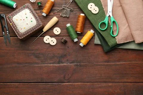 Flat lay composition with different sewing supplies on wooden table. Space .. Stock Photos
