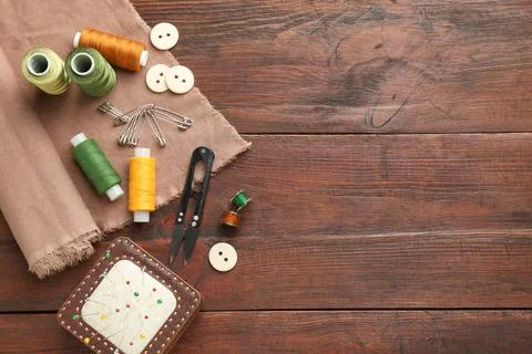 Flat lay composition with different sewing supplies on wooden table. Space .. Stock Photos