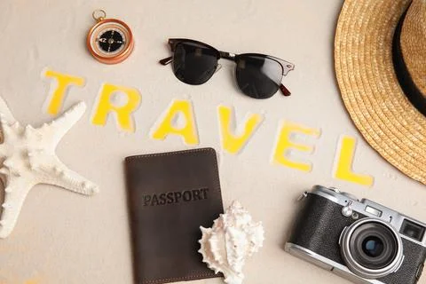 Flat lay composition with different tourist objects and word TRAVEL on sand Foto stock