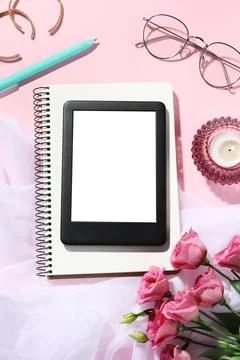 Flat lay composition with e-book reader, notebook and glasses on pink backg.. Stock Photos