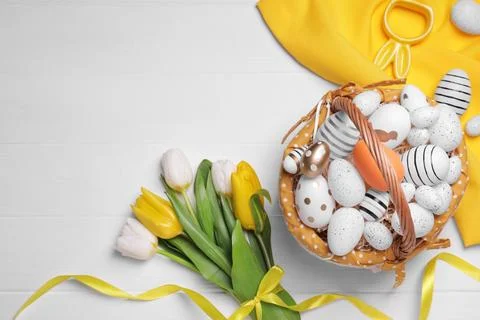 Flat lay composition with Easter eggs in basket and tulips on white wooden .. Stock Photos