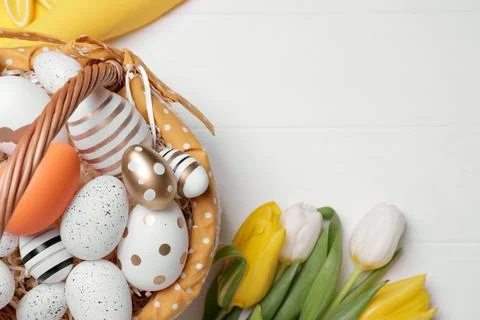 Flat lay composition with Easter eggs in basket and tulips on white wooden .. Stock Photos