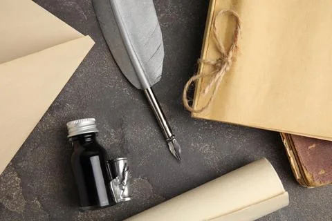 Flat lay composition with feather pen and bottle of ink on grey table Stock Photos