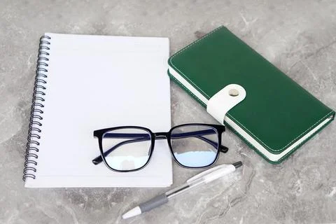 A flat lay composition featuring an open spiral notebook, a pair of eyeglasses,  Foto stock