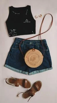 Flat lay composition with female top, denim shorts, sandals and a wicker rattan Stock Photos