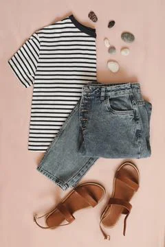 Flat lay composition with female top, denim shorts, sandals and a wicker rattan Stock Photos