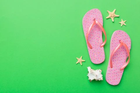 Flat lay composition with flip flops and seashell on colored background. Spac Stock Photos