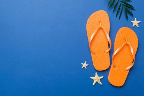Flat lay composition with flip flops and seashell on colored background. Spac Stock Photos