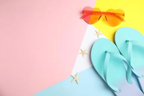 Flat lay composition with flip flops and sunglasses on color background. Spac Stock Photos