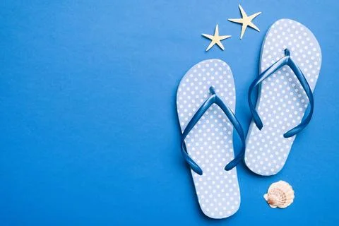 Flat lay composition with flip flops and seashell on colored background. Spac Stock Photos