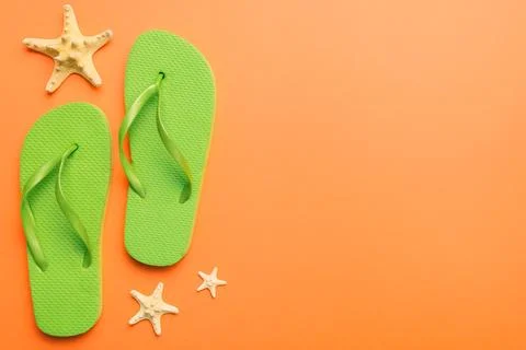 Flat lay composition with flip flops and seashell on colored background. Spac Stock Photos