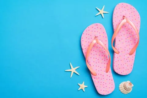 Flat lay composition with flip flops and seashell on colored background. Spac Stock Photos