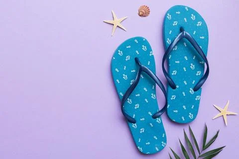 Flat lay composition with flip flops and seashell on colored background. Spac Stock Photos
