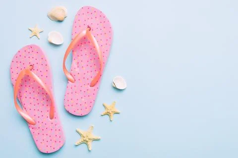 Flat lay composition with flip flops and seashell on colored background. Spac Stock Photos