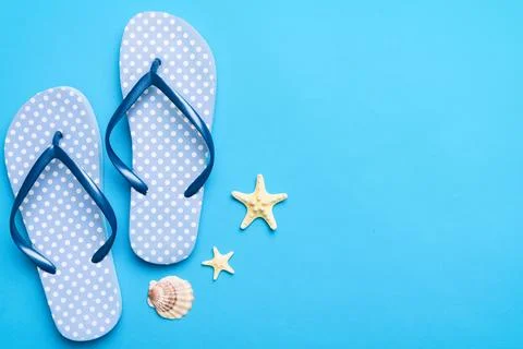 Flat lay composition with flip flops and seashell on colored background. Spac Stock Photos