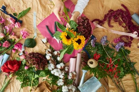 Flat lay composition florist creates a bouquet on craft paper and pink Stock Photos