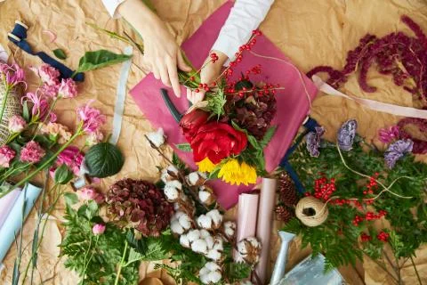 Flat lay composition florist creates a bouquet on craft paper and pink Stock Photos