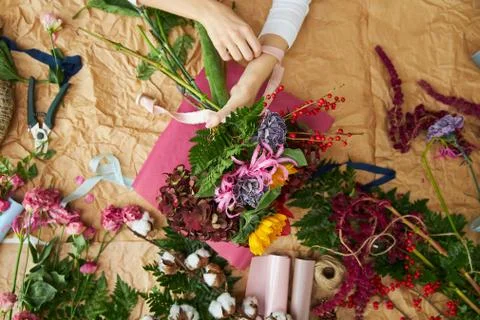 Flat lay composition florist creates a bouquet on craft paper and pink Stock Photos