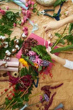 Flat lay composition florist creates a bouquet on craft paper and pink Stock Photos