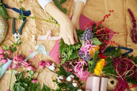 Flat lay composition florist creates a bouquet on craft paper and pink Stock Photos