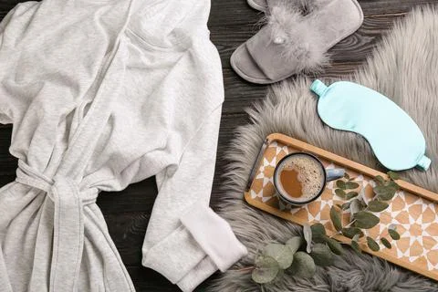 Flat lay composition with fluffy slippers and bath robe on black wooden backg Stock Photos