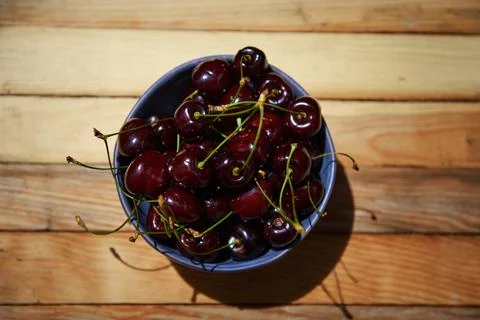 Flat lay composition of fresh ripe ready-to-eat purple cherries in a blue cer Stock Photos