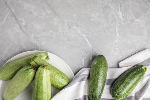 Flat lay composition with fresh ripe zucchini on grey marble background. Spac Stock Photos
