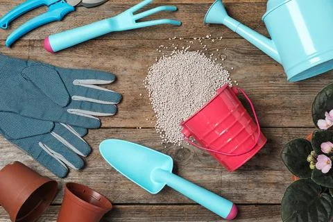 Flat lay composition with gardening tools, chemical fertilizer and plant on w Stock Photos