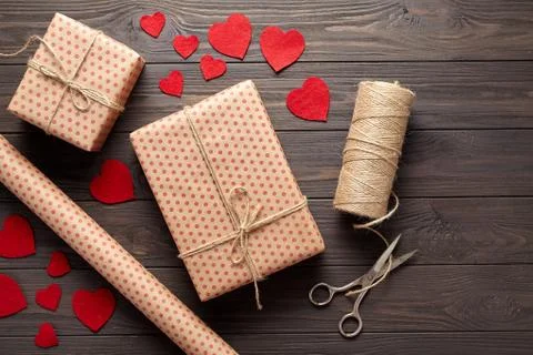 Flat lay composition with gifts, scissors, wrapping paper, twine, woolen hearts Stock Photos