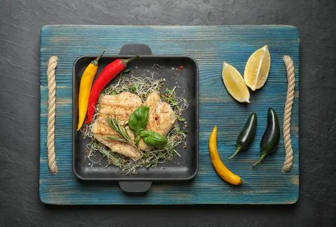 Flat lay composition with grilled fish on black table Stock Photos