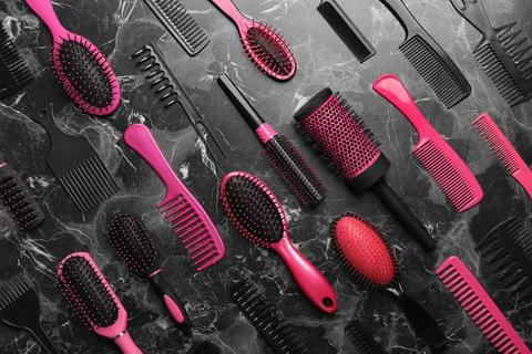 Flat lay composition with hair brushes and combs on black marble background Stock Photos