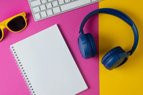 Flat lay composition with headphones, sunglasses, notepad and keyboard on a y Stock Photos