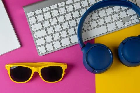 Flat lay composition with headphones, sunglasses, notepad and keyboard on a y Stock Photos