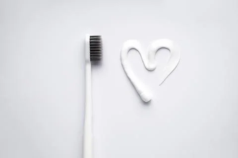 Flat lay composition heart shape made of toothpaste and white toothbrush on a Stock Photos