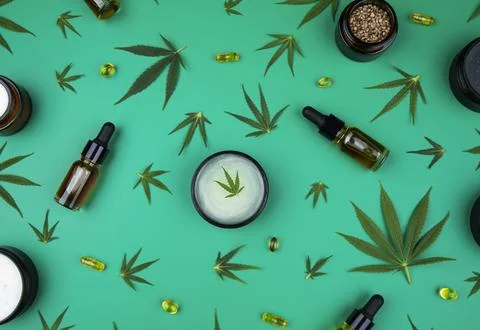 Flat lay composition with hemp oil and hemp leaves on green color background Stock Photos