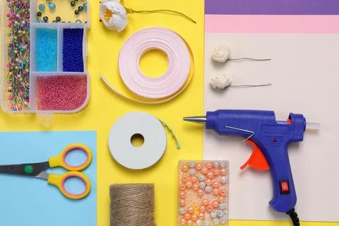 Flat lay composition with hot glue gun and handicraft materials on color back Stock Photos