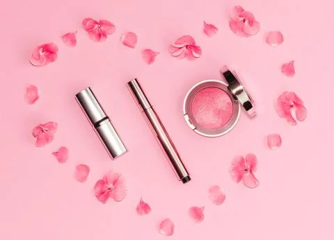 Flat lay composition with makeup products and pink flowers in a shape of heart Stock Photos