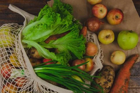 Flat lay composition with meshed eco shopping bag. Organic fruits and vegetab Stock Photos