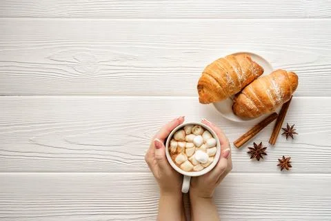 Flat lay composition with a mug of cocoa in female hands and croissants on a Stock Photos