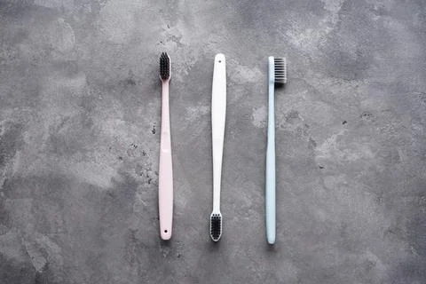 Flat lay composition of multi-colored toothbrushes with black bristles on a g Stock Photos