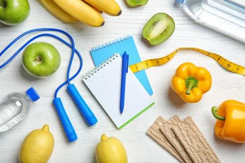 Flat lay composition with notebooks, healthy food and jumping rope on wooden  Stock Photos