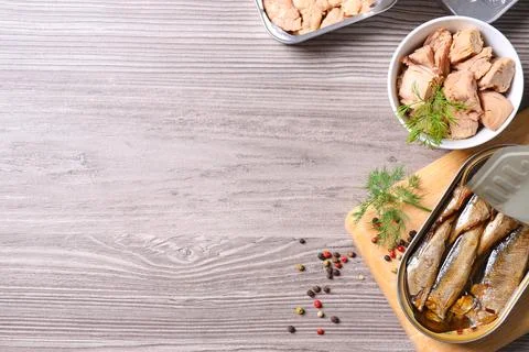 Flat lay composition with open tin can and fish meat on wooden table, space f 写真素材