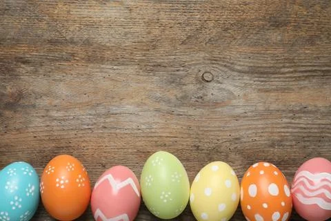 Flat lay composition of painted Easter eggs on wooden background, space for t Stock Photos