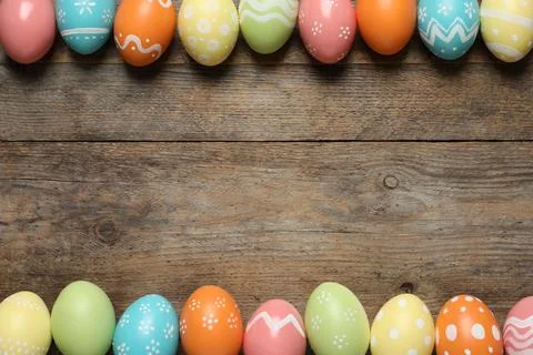 Flat lay composition of painted Easter eggs on wooden background, space for t Stock Photos