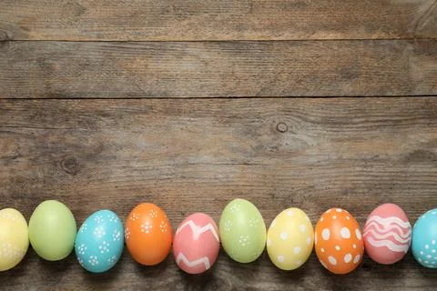Flat lay composition of painted Easter eggs on wooden background, space for t Stock Photos
