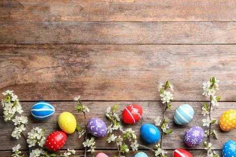 Flat lay composition with painted Easter eggs and blossoming branches on wood Stock Photos