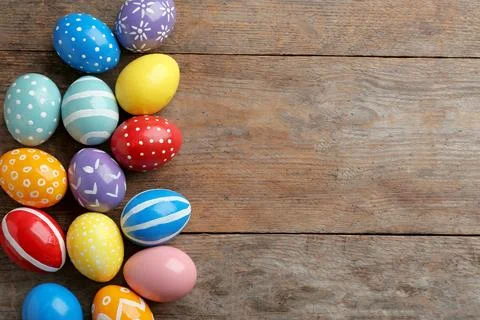 Flat lay composition of painted Easter eggs on wooden table, space for text 写真素材